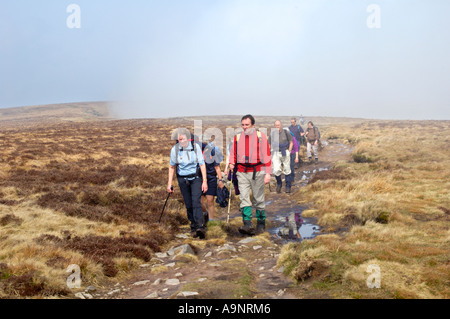 Groupe visite guidée à pied de nuages bas derrière sur l'Offa's Dyke sentier Hatterrall Ridge formant la frontière du pays de Galles et l'Angleterre UK Banque D'Images