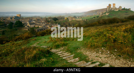 Château à l'abandon et le village de Corfe Castle in early morning light et un ciel clair avec des marches menant vers le bas de la colline Banque D'Images