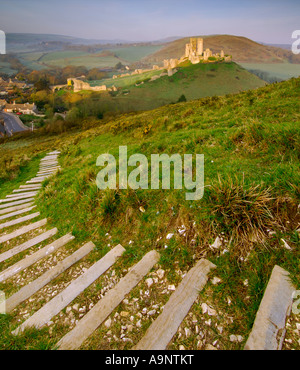 Château à l'abandon et le village de Corfe Castle in early morning light et un ciel clair avec des marches menant vers le bas de la colline Banque D'Images