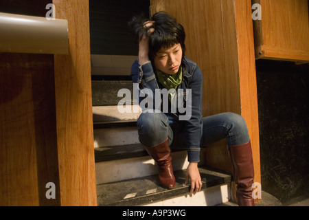 View of a young Asian woman sitting on steps Banque D'Images