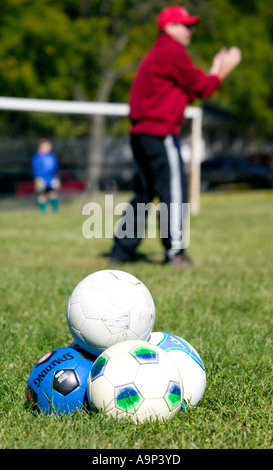 Tas de ballons de football sur terrain avec l'entraîneur Banque D'Images