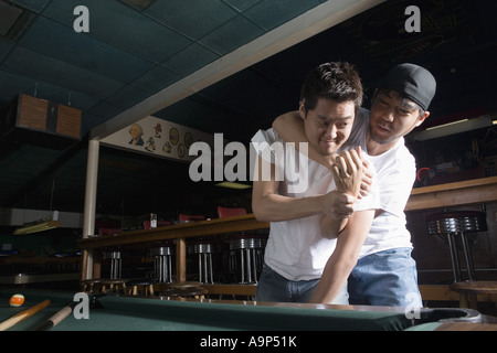 Deux jeunes hommes en jeans et t-shirts combats dans la salle de billard Banque D'Images