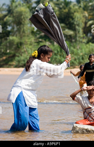 Blanchisserie indiennes (fille) dhobi de battre l'eau hors de vêtements après le lavage dans la rivière. L'Andhra Pradesh, Inde Banque D'Images