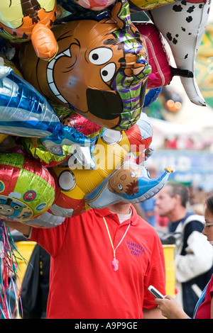 Vendeur de ballons tenant des ballons d'hélium de caractère à une foire. ROYAUME-UNI Banque D'Images