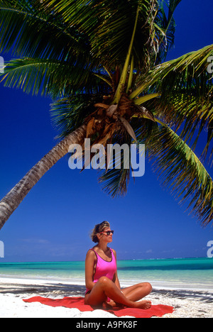 République dominicaine Punta Cana Bavaro Beach jeune femme de 25 ans sur une plage, assis sous un palmier au bord de la mer des Caraïbes Banque D'Images