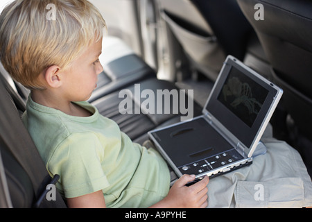 Garçon est assis dans la voiture avec un lecteur de dvd portable Banque D'Images