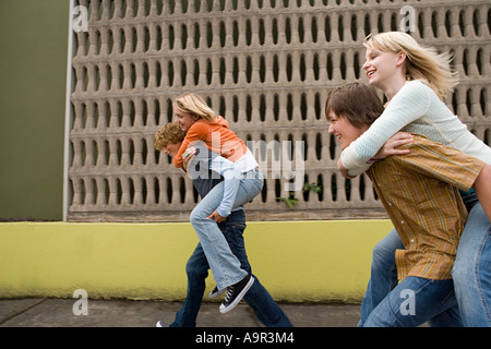 4 adolescents exécutant piggy back courses Banque D'Images