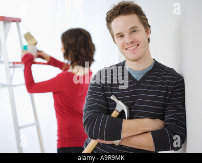 Man leaning on wall holding hammer Banque D'Images