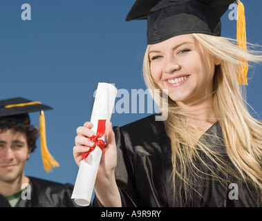 Woman wearing graduation cap and gown avec diplôme Banque D'Images