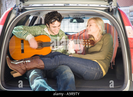 Couple assis à l'arrière de la voiture avec guitare Banque D'Images