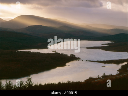 Arbres de la strie du soleil sur le Loch Garry pour une journée d'hiver orageux Ecosse Banque D'Images