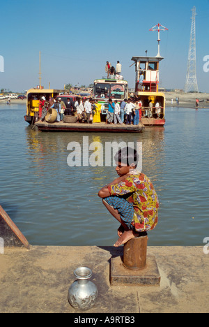 Un ferry bondé arrive et un jeune garçon attend au terminal des ferries près de Faridpur. Bangladesh Banque D'Images