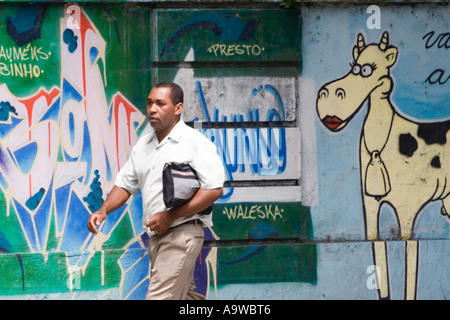 Business man walking passé mur couvert de graffitis Banque D'Images