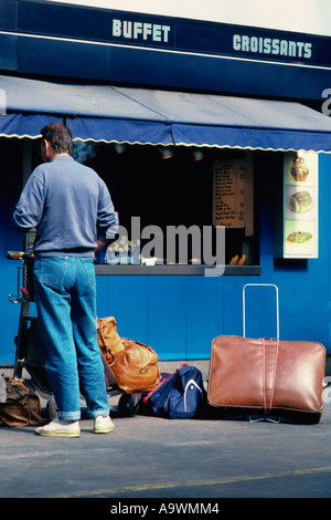France Paris Gare d'Austerlitz passager en jeans bleus, vêtu de façon décontractée, achetant un en-cas dans un kiosque alimentaire à prendre le train. Banque D'Images