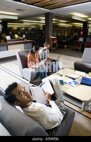 Les élèves d'ordinateurs portables dans l'étude de canapés assis sur la bibliothèque Banque D'Images