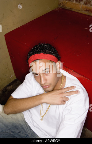 Portrait d'un jeune homme dans la mode hip-hop assis sur le plancher Banque D'Images
