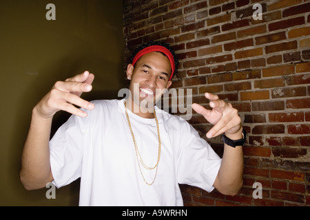 Portrait d'un jeune homme dans la mode hip-hop gangsta les gestes de la main montrant permanent Banque D'Images