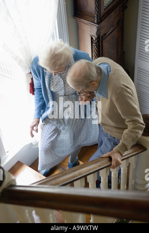 Aider l'autre couple grimper les escaliers avec précaution Banque D'Images