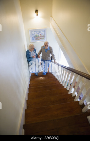 Aider l'autre couple grimper les escaliers avec précaution Banque D'Images