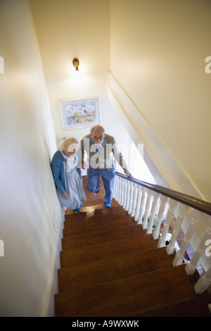 Aider l'autre couple grimper les escaliers avec précaution Banque D'Images