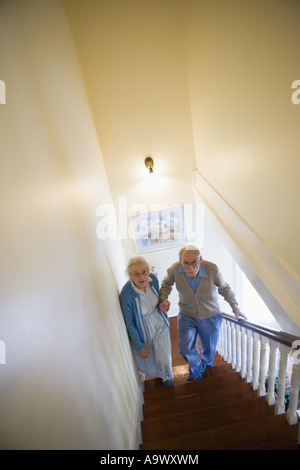 Aider l'autre couple grimper les escaliers avec précaution Banque D'Images