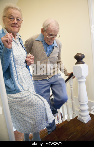 Aider l'autre couple grimper les escaliers avec précaution Banque D'Images