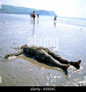 Un homme étendu le ventre en l'air s'est effondré sur une plage de sable couvert de Borth Ceredigion, pays de Galles UK Banque D'Images