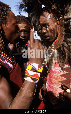 Lolgorian, au Kenya. Manyatta Masaï Siria ; 'tête de lion' moran avec coiffe de plumes symbolique avec des perles et des cauris. Banque D'Images