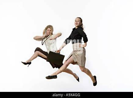 Deux femmes sautant en l'air habillé en tenue d'affaires conservateur Banque D'Images