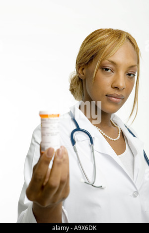 Jeune femme médecin dans une blouse blanche et stéthoscope propose un pot de médicaments prescrits pour le patient Banque D'Images