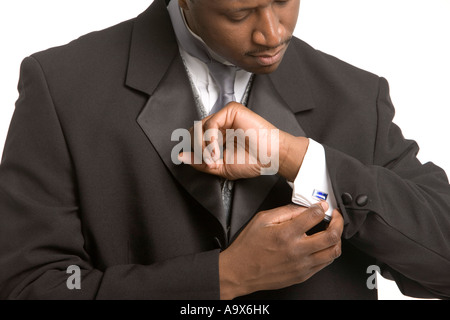 Séduisant jeune homme noir portant des vêtements de mariage formel son réglage cufflink Banque D'Images