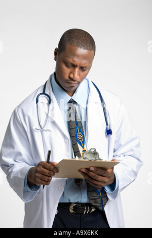 Jeune médecin vêtu d'un manteau blanc et de l'information lecture stéthoscope un presse-papiers Banque D'Images