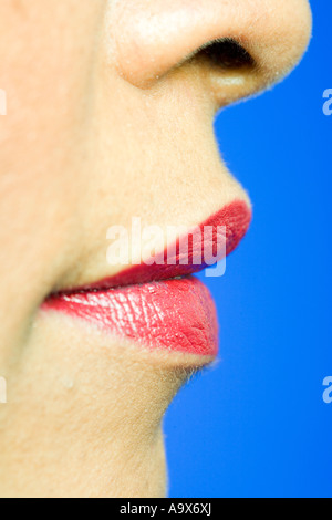 La bouche et le nez d'une jolie femme porter du rouge à lèvres sur un fond bleu Banque D'Images