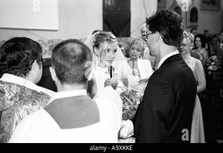 Pologne, Lodz, mariée et le marié l'échange de vœux en face de prêtre à l'église (B&W) Banque D'Images