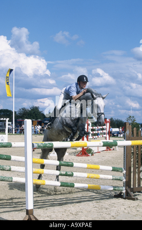 Cavalier et son cheval sautant par-dessus montrent jump. Banque D'Images