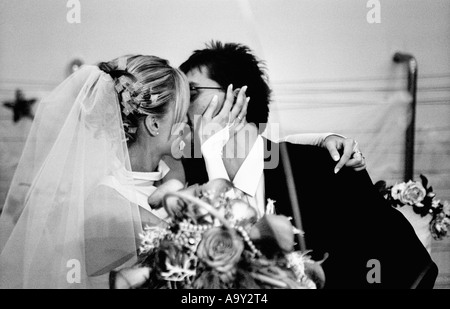 Pologne, Lodz, Bride and Groom kissing at wedding party (B&W) Banque D'Images