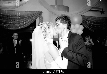 Pologne, Lodz, Bride and Groom kissing at wedding party, vue latérale (B&W) Banque D'Images