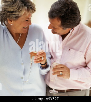 Couple d'âge moyen de boire du vin de rire Banque D'Images