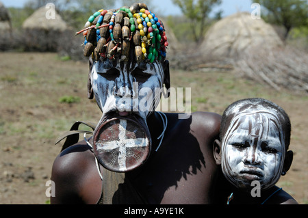 Femme peint en blanc avec une lèvre de la plaque et son bébé de la gens Mursi près de Jinka Ethiopie Banque D'Images