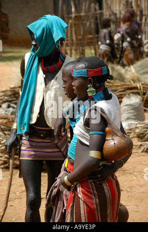 L'homme habillé en couleurs avec deux jeunes femmes du marché de Dimeka peuple Hamar Ethiopie Banque D'Images