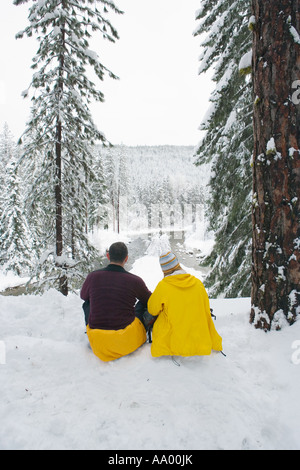 Couple sitting in snow enjoying view de la rivière Wenatchee, Washington USA Banque D'Images