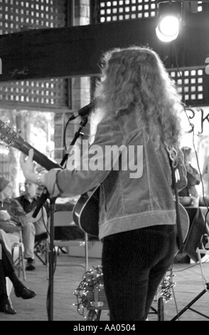 Femme caucasienne (25-30) se produisant passionnément sur scène dans un festival de musique en plein air aux États-Unis, engageant la foule avec son énergie vibrante et sa musique. Banque D'Images