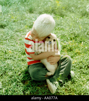 Petit chiot boy hugging outdoors Banque D'Images