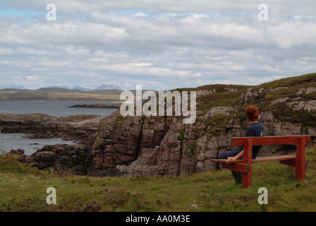 Adolescent assis sur un banc en bois donnant sur la mer, l'Écosse, au Royaume-Uni. Banque D'Images