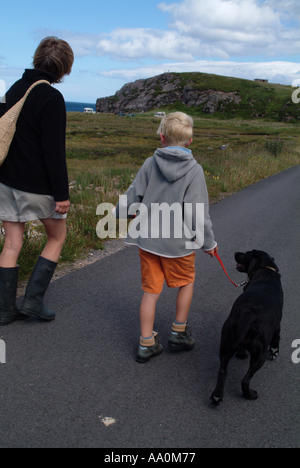 La mère et l'enfant de marcher un chien labrador noir le long d'un sentier du littoral Banque D'Images