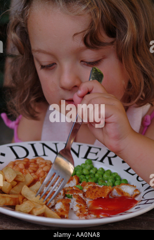 Girl eating chips fish fingers les pois et les haricots Banque D'Images