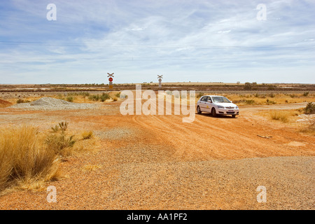 Voiture en face de drones et de passage à niveau sans barrière sur la route de gravier à l'ouest de l'Australie Banque D'Images