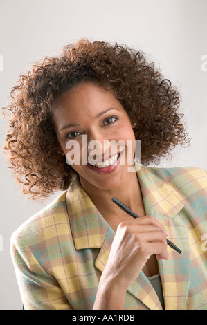 D'AFFAIRES DE COULEUR FEMME ÂGE 30PLUS TENIR PEN en souriant à l'appareil photo Banque D'Images