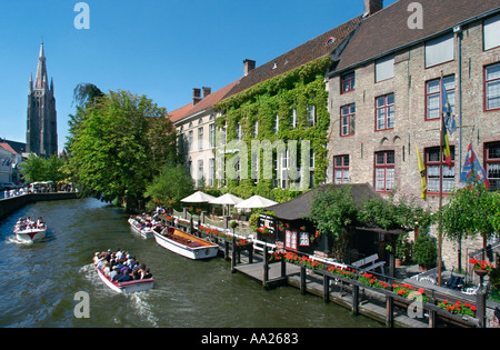 Bruges, Belgique. Voyage en bateau sur un canal dans le centre de la vieille ville avec Onze Lieve Vrouwekerk derrière. Banque D'Images