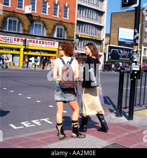 Les jeunes femmes à la mode sac à dos sac à main sac à dos avec les gens en attente de style pour changer les feux de circulation dans une rue d'East London UK KATHY DEWITT Banque D'Images